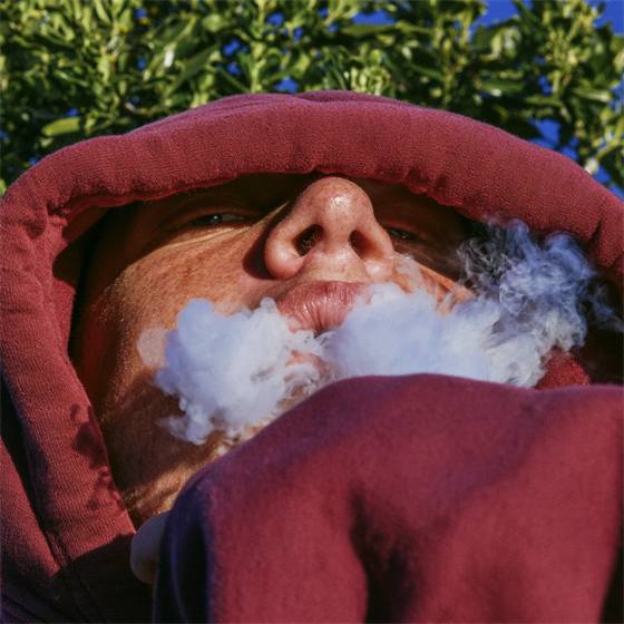 A man in a hood exhaling a cloud of vapour