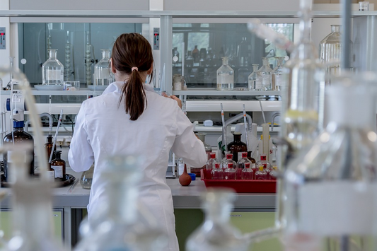 scientist in white lab coat working in a lab among equipment