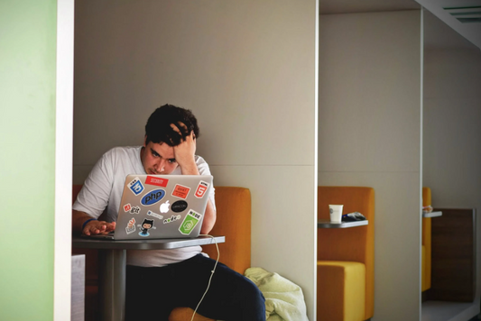 stressed person sitting at library study pod staring at laptop