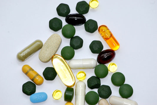 assortment of supplements, including tablets and capsules, of various sizes on a gray surface
