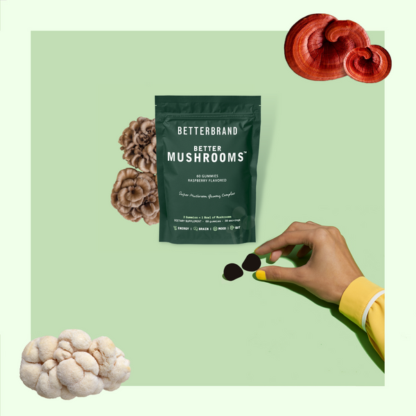 Hand holding yellow and black mushroom gummies near BetterMushrooms supplement package and three mushroom types on green background