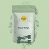 Front view of Nasal Strips pouch showcasing resealable green packaging and three black sample strips on a pale green botanical background